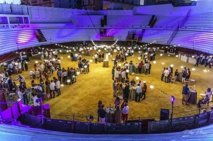 Interior de la plaza de toros decorado para evento con iluminación ambiental y mesas