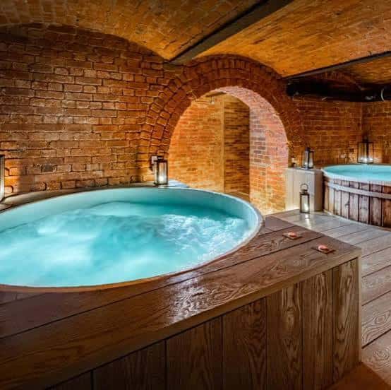Interior del spa subterráneo con jacuzzi de agua azul y paredes de ladrillo