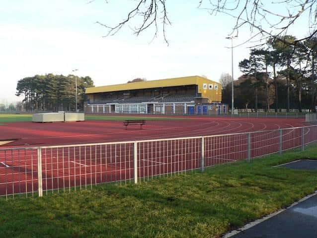 Vista lateral de la pista de atletismo con gradas amarillas y valla perimetral