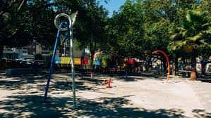 Parque infantil con toboganes y columpios en zona arbolada