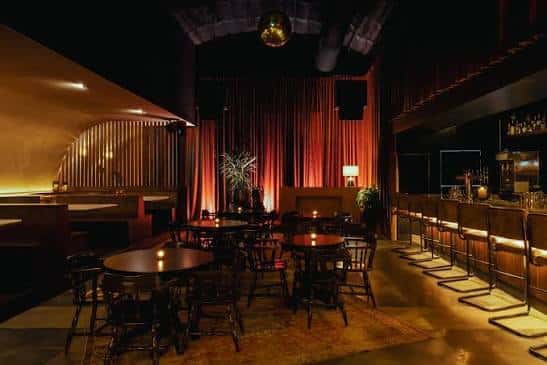 Interior del East End Ballroom con mesas, cortinas rojas y barra de bar