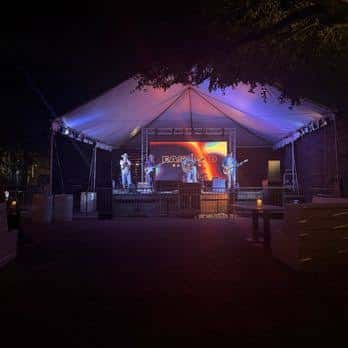 Concierto en vivo al aire libre bajo una carpa iluminada