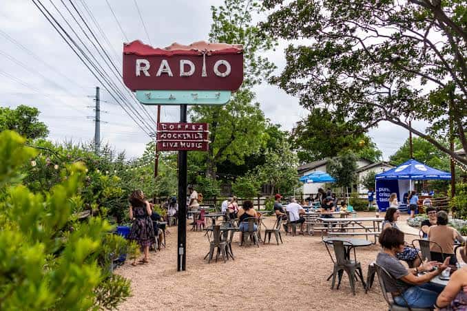 Vista del patio exterior de Radio East con el letrero principal y mesas de picnic