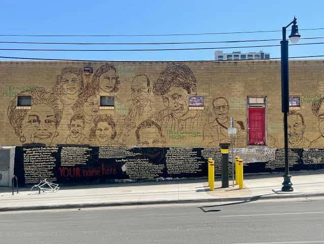 Mural artístico en la pared de un edificio mostrando retratos de figuras culturales