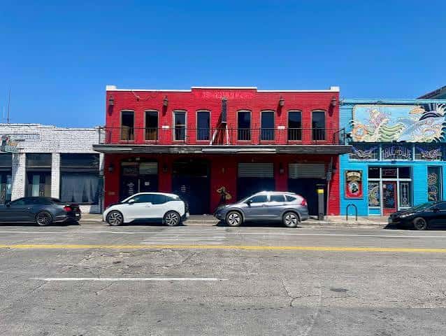 Fachada roja de un local de entretenimiento con coches aparcados frente a él