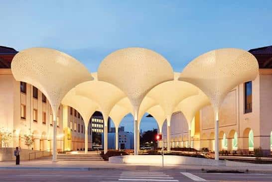 Fachada iluminada del Museo Blanton al atardecer con las esculturas de sombra destacadas