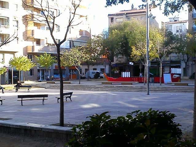 Plaza de Santa Eugènia con el barco rojo y bancos en primer plano
