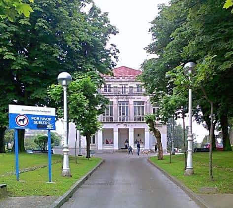 Entrada principal al edificio con el camino de acceso y árboles frondosos