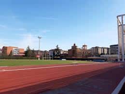 Vista panorámica del campo de atletismo y césped del Campo de la Juventud con edificios urbanos al fondo