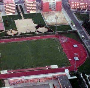 Vista aérea del complejo deportivo con pista de atletismo roja y campo de fútbol verde