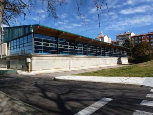 Vista exterior del Complejo Deportivo Eras de Santa Marina con fachada de cristal y estructura metálica bajo cielo azul