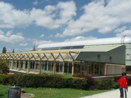 Fachada lateral del polideportivo con estructura de madera y paneles solares en el techo