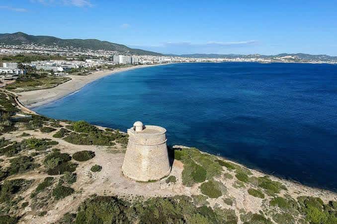 Vista aérea de la torre de vigilancia en Playa d'en Bossa con el mar azul y la costa al fondo
