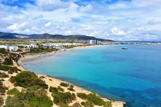 Panorámica de la bahía de Playa d'en Bossa con arena, vegetación y edificios costeros