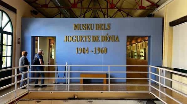 Entrada principal del Museo dels Joguets de Dénia con letrero dorado y visitantes en el vestíbulo
