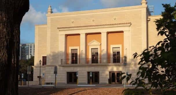 Fachada del auditorio al atardecer con luz cálida y árboles en primer plano