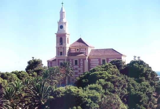 Vista panorámica del Templo de Poniente en Motril, con su torre campanario y fachada rosa rodeada de vegetación