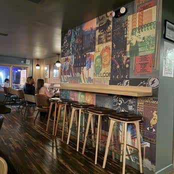 Interior del bar con decoración de murales musicales y barra de madera