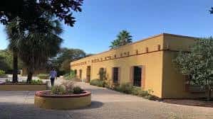 Fachada exterior del edificio de Fiesta Gardens con arquitectura de estilo español y cielo despejado