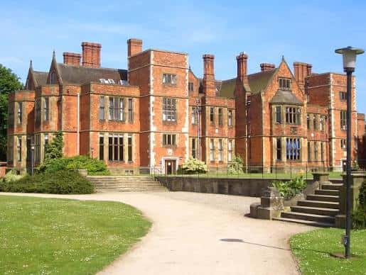 Vista frontal de Heslington Hall con fachada de ladrillo rojo y jardines bien cuidados