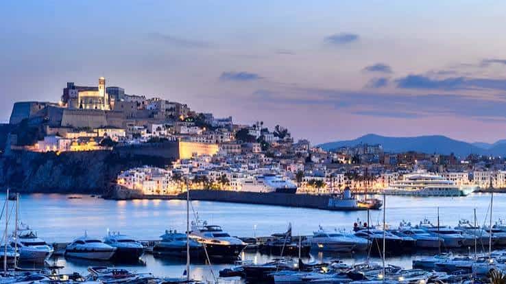 Puerto de Ibiza con Dalt Vila iluminado al anochecer y embarcaciones en primer plano