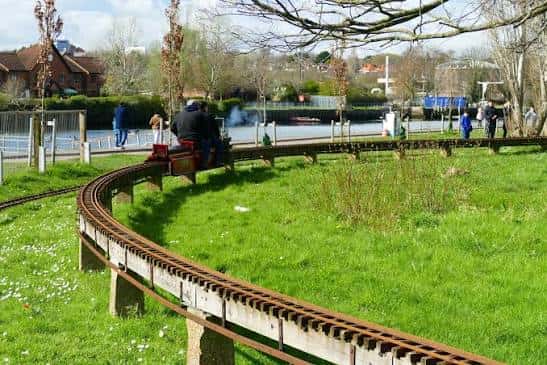 Tren de juguete en el parque con niños y adultos disfrutando