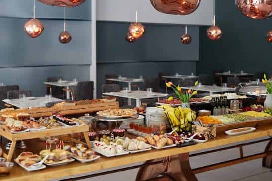 Buffet de desayuno en el restaurante del Axel Hotel con variedad de alimentos y decoración moderna