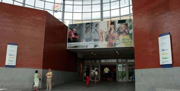 Entrada principal del centro comercial con cartel de bienvenida y personas accediendo