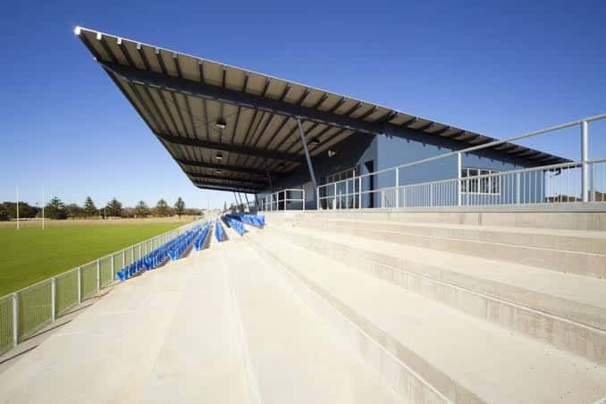 Vista exterior del estadio con gradas de hormigón y techo inclinado bajo un cielo azul