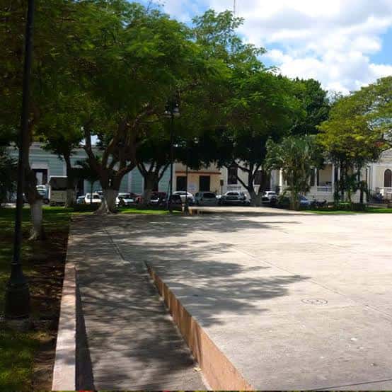 Plaza principal del parque con árboles y bancos bajo la sombra