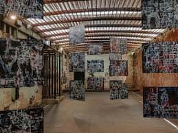 Interior del espacio de eventos con paredes de ladrillo envejecidas y una instalación de arte colgante