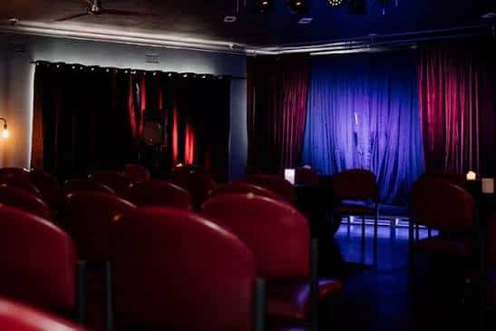 Interior del Newcastle Comedy Club con butacas rojas y escenario iluminado