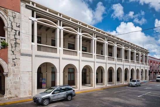 Vista lateral del Centro Cultural Olimpo con coches estacionados frente a sus arcos coloniales