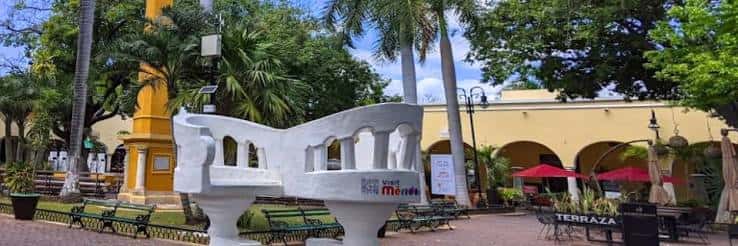 Detalle del monumento blanco con vista de los arcos coloniales y mesas de terraza
