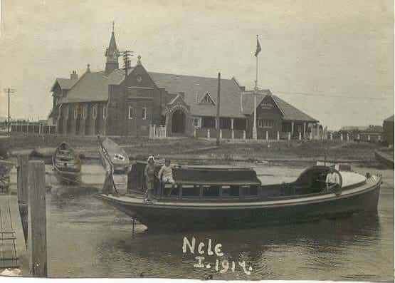 Vista histórica del edificio junto al muelle con embarcaciones en primer plano