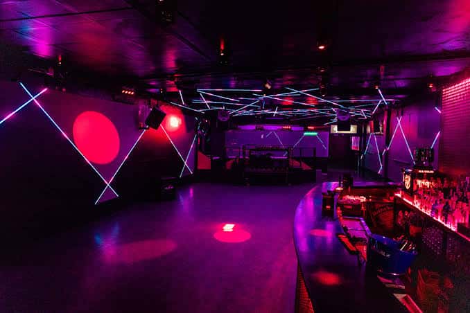 Interior del club con iluminación de neón y barra de bar