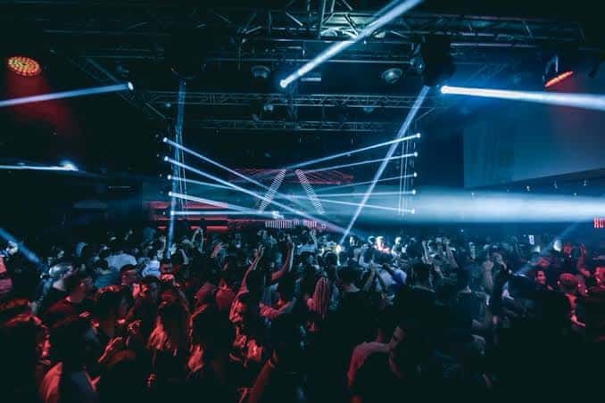 Pista de baile llena de gente con luces de neón en Spook Club