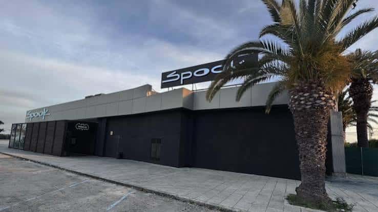 Fachada exterior del local Spook con palmeras y letrero iluminado