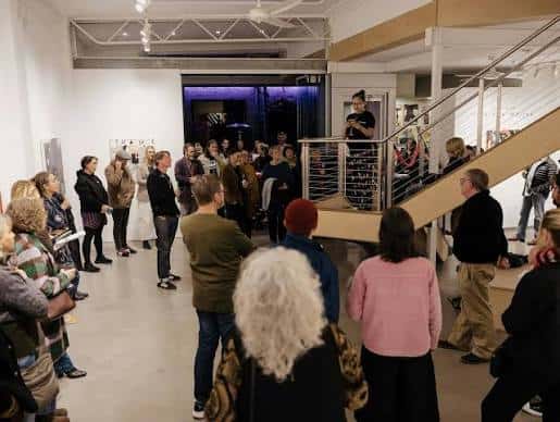 Evento de inauguración en el interior de Straitjacket con público asistiendo a una charla
