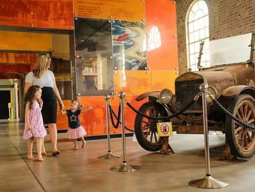 Exposición de museo con familia y automóvil histórico