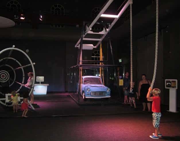 Exhibición interactiva con automóvil azul y visitantes