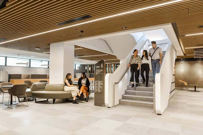 Interior del hall principal con escalera moderna y zona de descanso para estudiantes