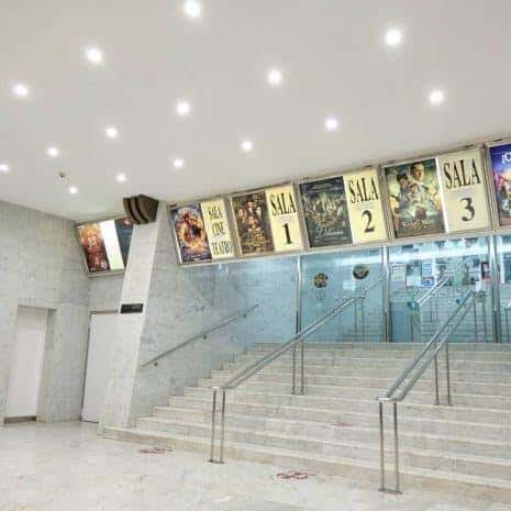 Hall de entrada con escaleras y carteles de las salas de cine