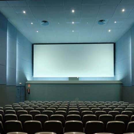 Sala de cine moderna con pantalla blanca y butacas grises