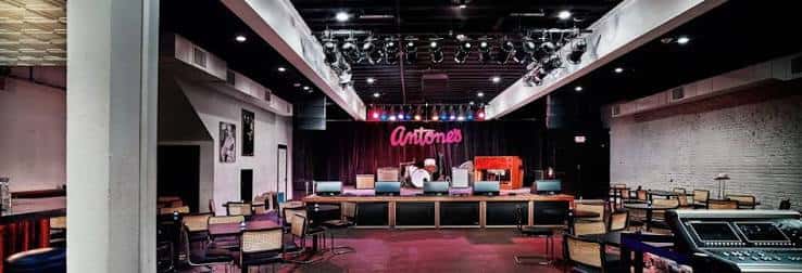 Interior del club con escenario, luces de escenario y mesas dispuestas para eventos