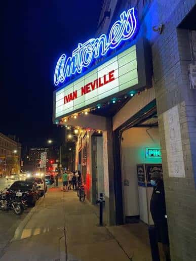 Entrada principal de Antone's por la noche con letrero luminoso y cartel de artista en cartelera