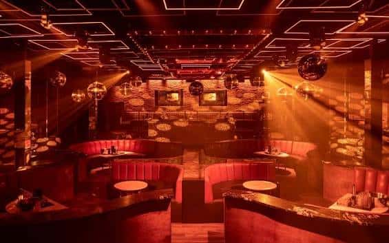 Interior del club nocturno Mayfair con iluminación roja y mesas de estar