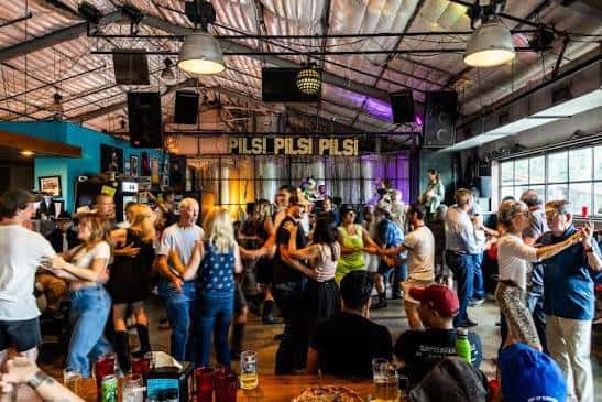 Interior del local con gente celebrando y bailando bajo luces de ambiente