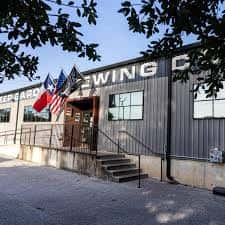 Fachada exterior del edificio de The Austin Beer Garden Brewing Company con banderas estadounidenses
