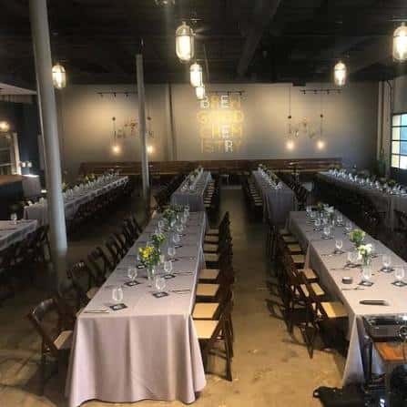 Sala de eventos preparada con mesas largas y mantelería para una celebración